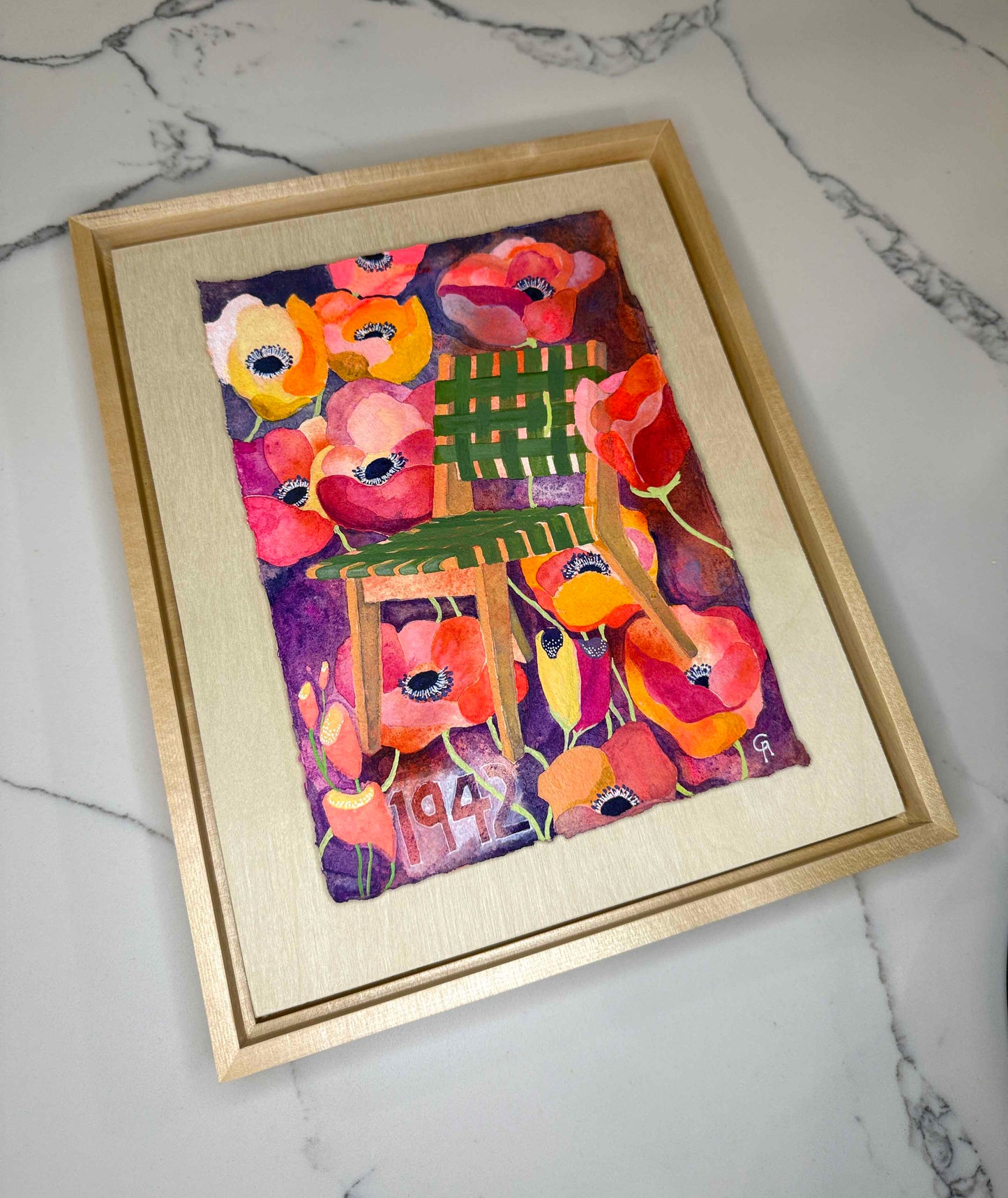 Framed artwork of a colorful chair surrounded by flowers on a marble surface