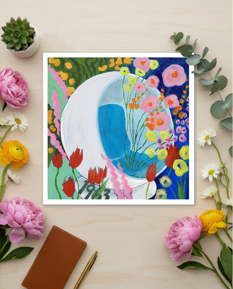 Artistic depiction of a blue whale surrounded by colorful flowers on a light surface with flowers and a notebook.