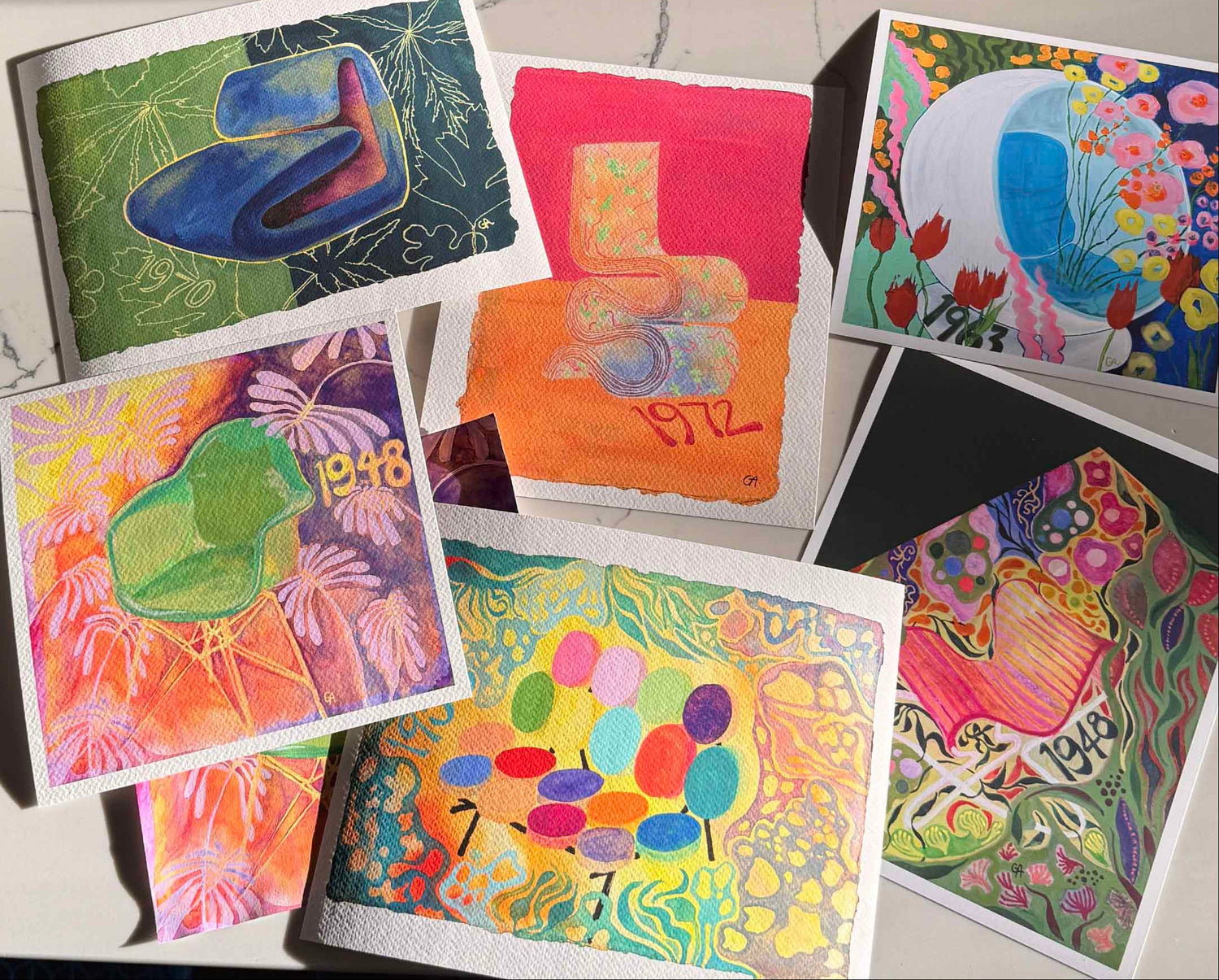 collection of bright colorful gallery quality giclee prints on white marble kitchen counter archival watercolor paper impeccable vibrant chairs blossoms flowers chair design furniture architecture garden