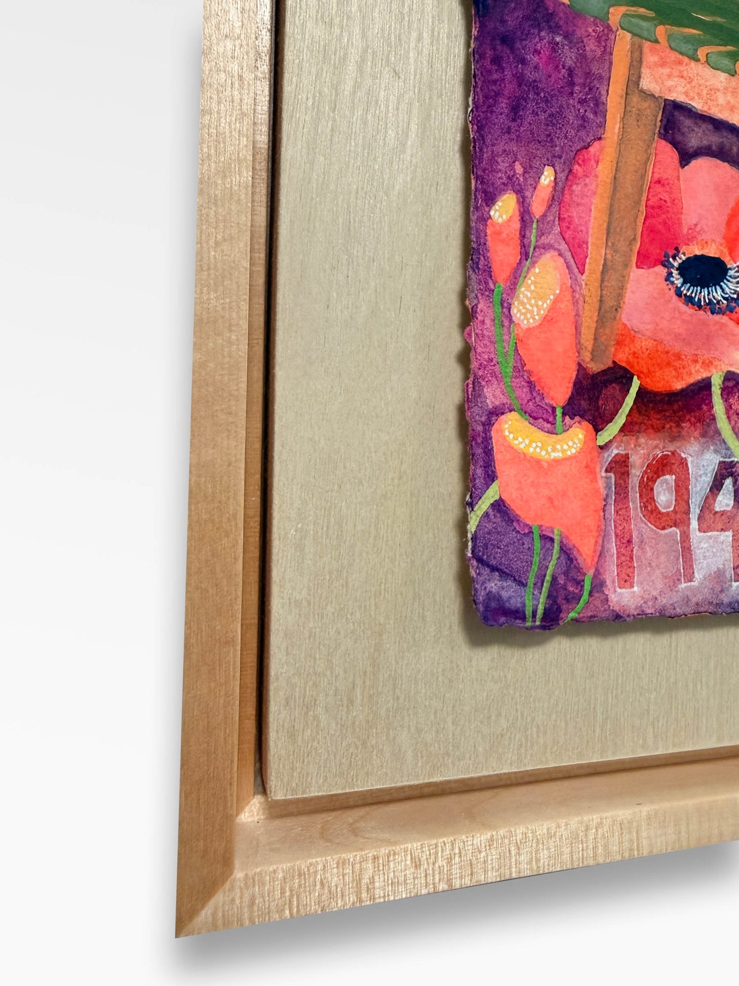 Framed artwork of a colorful chair surrounded by flowers on a neutral grey wall. maple frame with a float board and watercolor art piece floating with a shadow gap on the board. bright red and pink anemone flowers with yellow and purple accents surround a green lattice chair designed in 1942 in scandinavia. modern design with a lush surround of blooms. tiny pistons are visible in the centers of several of the anemones.