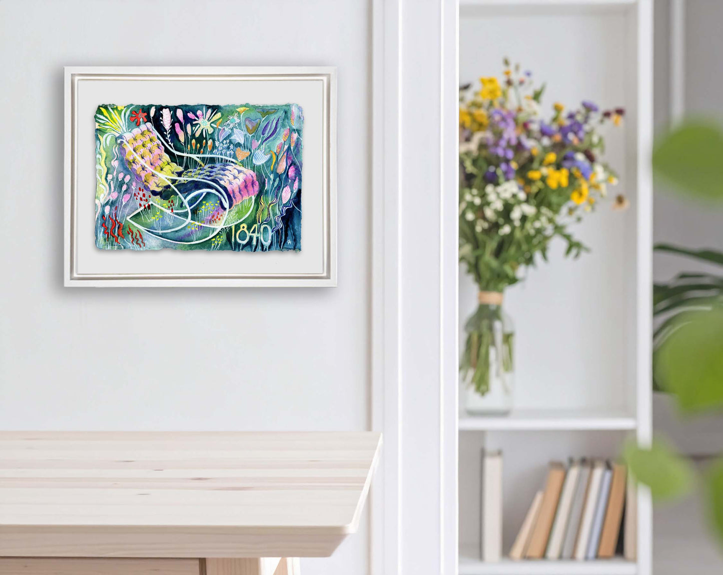 Framed artwork with colorful floral around a chair design on a white wall. bouquet in the background next to a large house plant. bookshelf and books, kitchen table in light wood. lots of color watercolor on a recycled cotton cold press textured paper with raw ripped edge. florals surround a lounge tufted chair with curvy classic lines from 1840